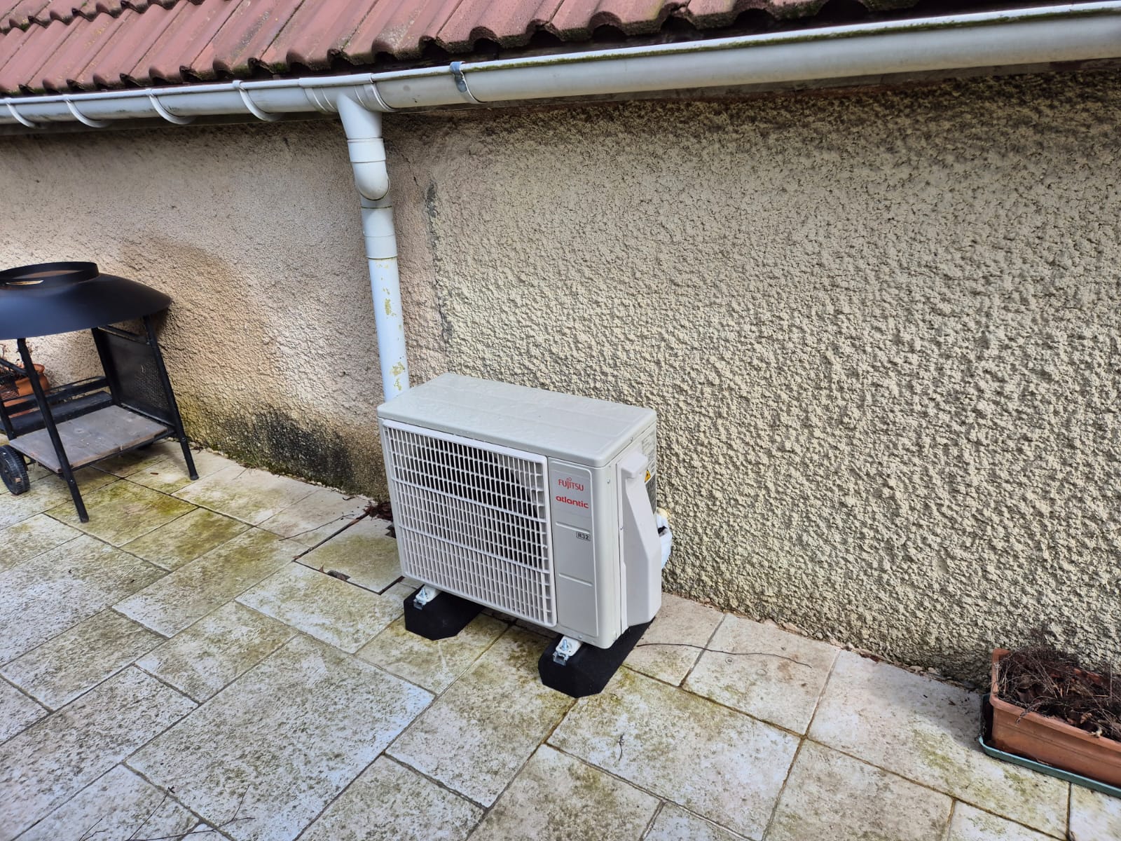 Groupe extérieur Fujitsu Atlantic R32 du chauffe-eau thermodynamique split Calypso posé sur plots anti-vibration en façade à Montigny-le-Bretonneux