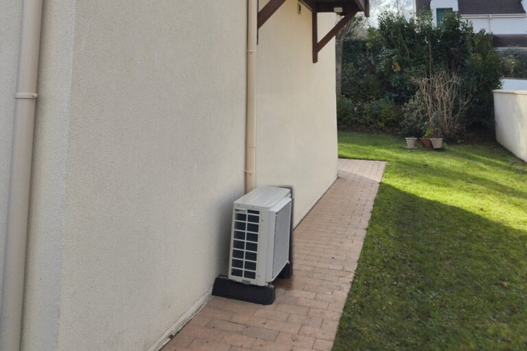 Groupe extérieur Daikin monosplit posé sur socle au pied du pignon d'une maison à Morainvilliers, liaisons dans une goulotte beige